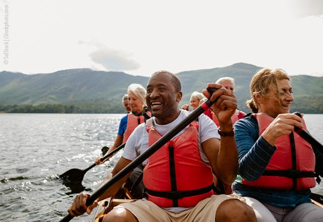 People using paddles on a boat and smiling