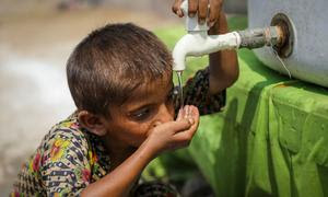 Un niño de 5 años bebe agua de un punto de agua instalado por UNICEF en un campamento provisional del distrito de Larkana, provincia de Sindh, Pakistán.