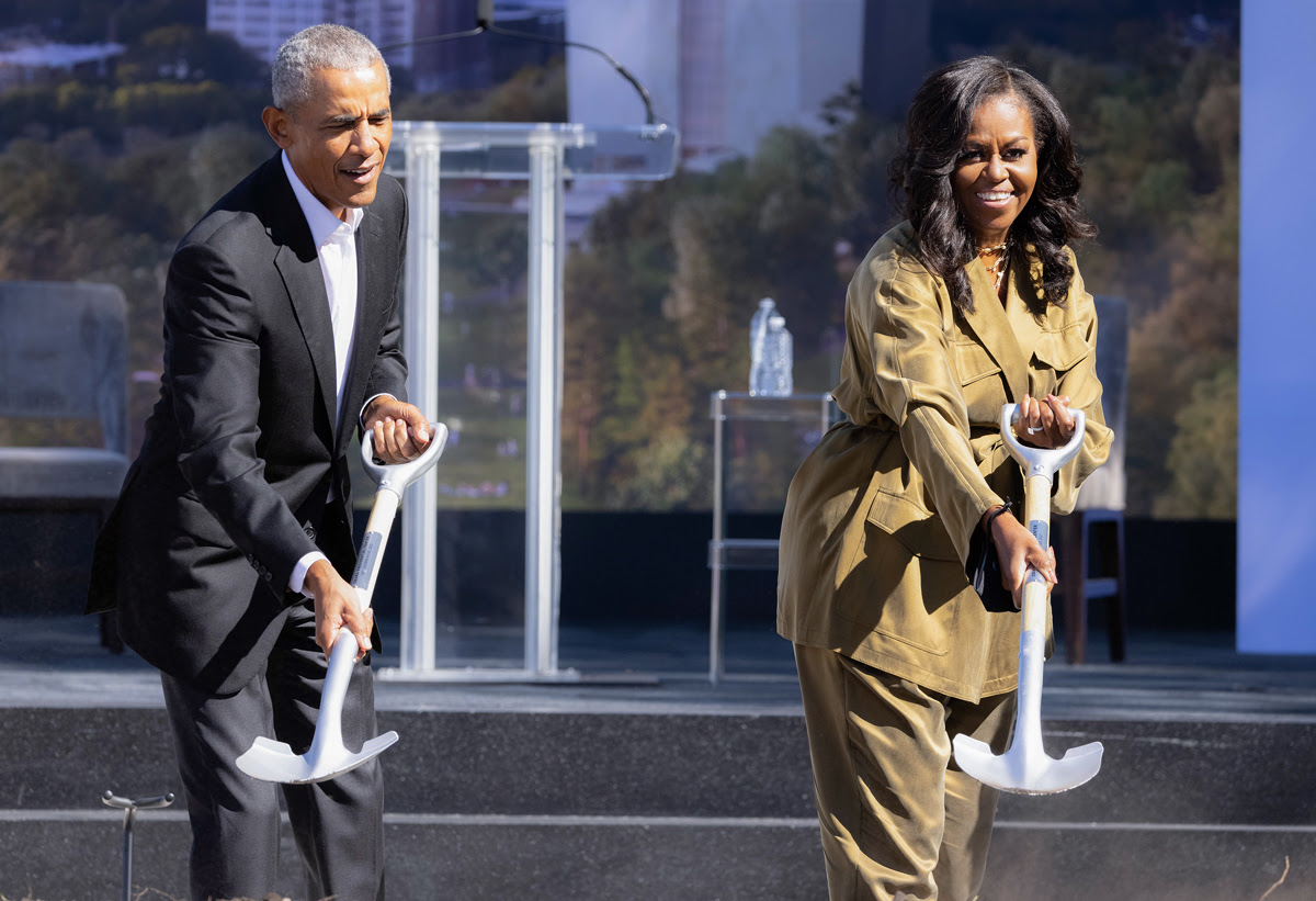 President and Mrs. Obama are dressed in business clothing and smiling at the camera as they wield shovels at the OPC groundbreaking