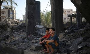 Dos niños sentados entre los escombros de lo que queda de su casa en la ciudad de Rafah, en el sur de la Franja de Gaza.