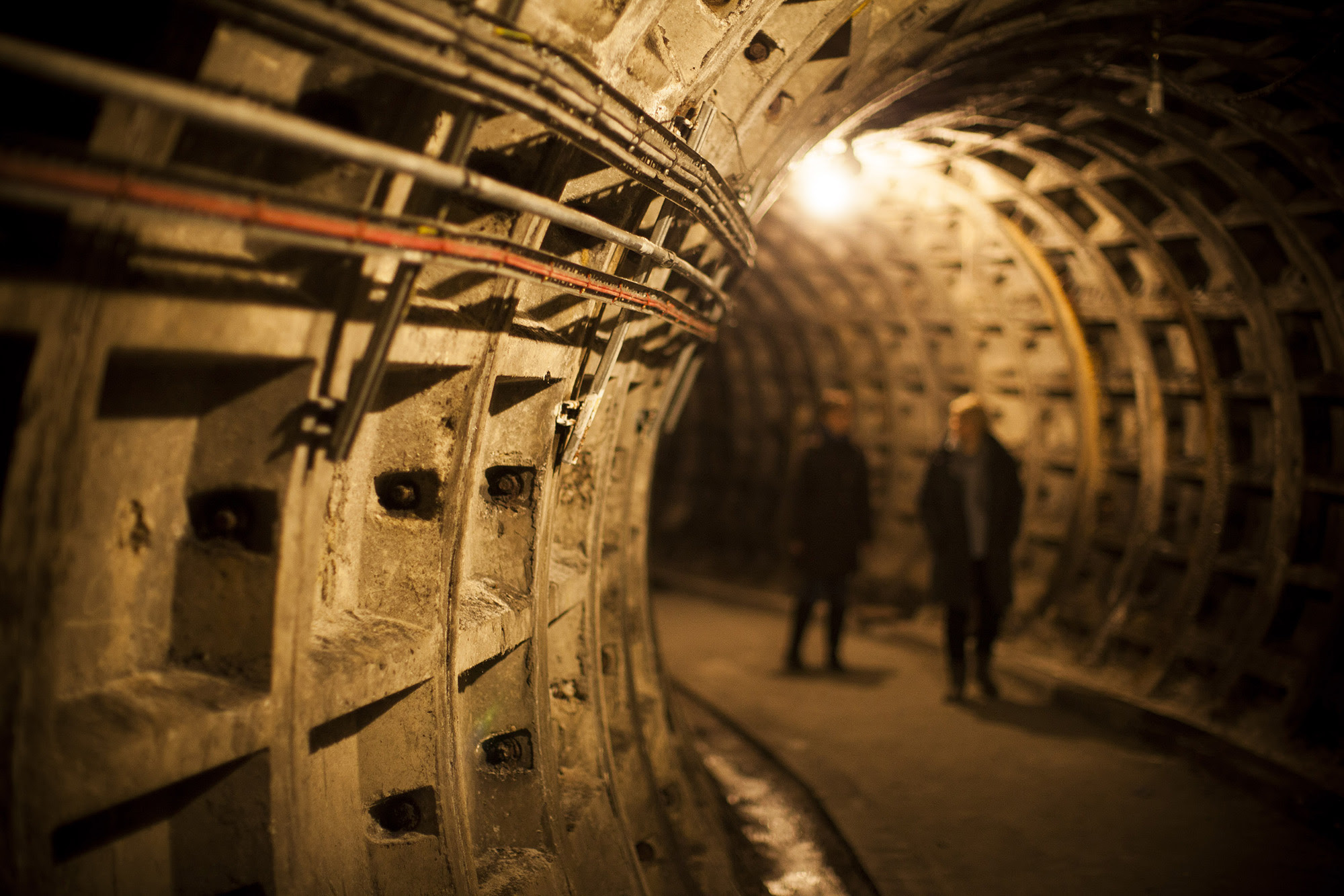 Two people walking around a curving underground tunnel