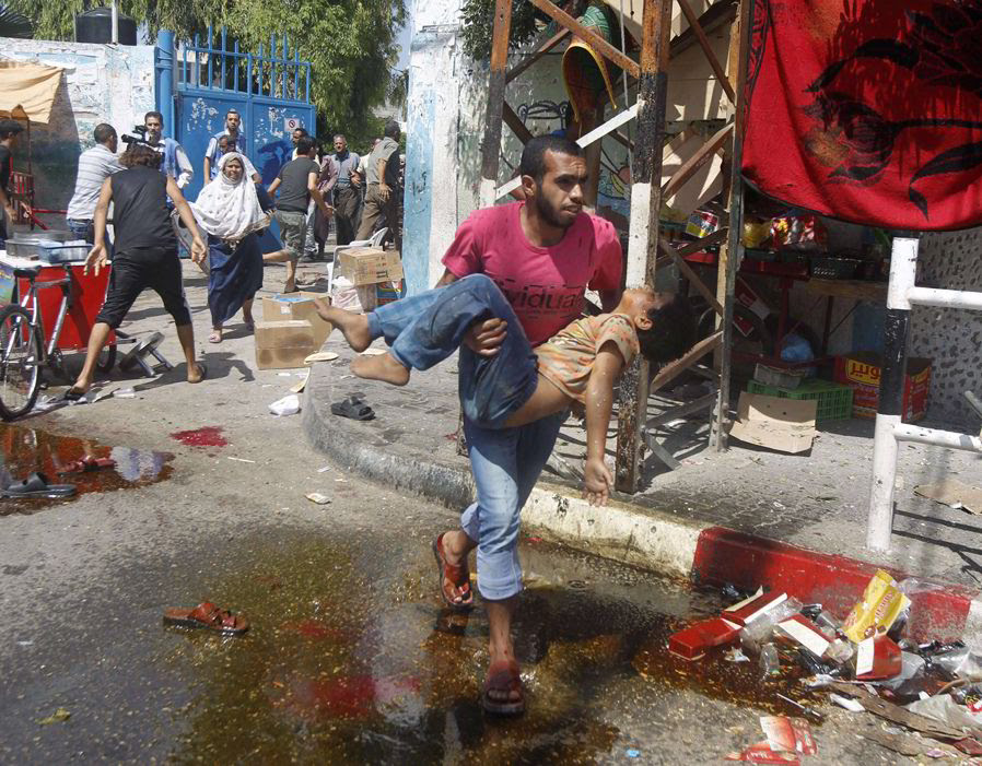 A Palestinian man carries an injured child following an Israeli military strike on a UN school in Rafah, in the southern Gaza Strip on August 3, 2014. At least 10 people were killed in a fresh strike on a UN school in southern Gaza which was sheltering Palestinians displaced by an Israeli military offensive, medics said