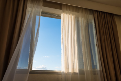 Window with open drapes and a view of a sunny blue sky