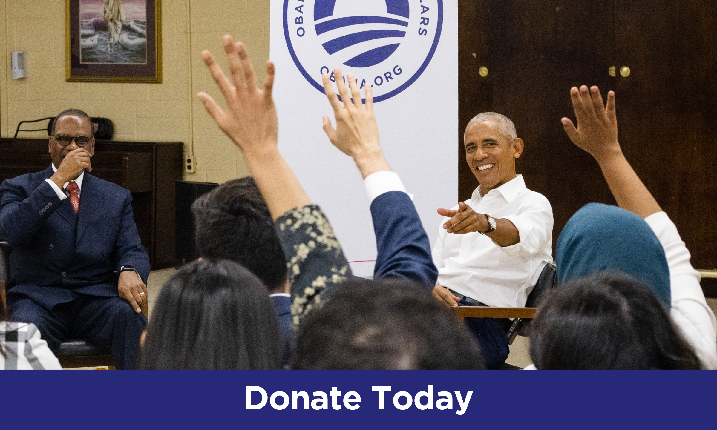 President Obama smiles big while pointing at several engaged people in the audience with their hands raised.