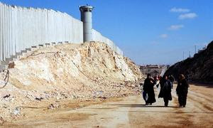 Mujeres palestinas caminando a lo largo del muro de separacón cerca de Ramalá, en Cisjordania.