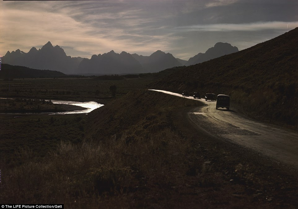 The route to Jackson Hole from the east: Cars pictured on Blackrock Creek with the Grand Tetons in the background
