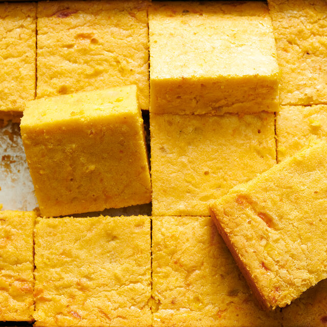 A tray of sopa Paraguaya, a dense and cheesy cornbread. It is cut into 12 squares, with some removed from the pan. 