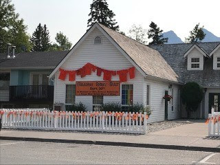 Photo of Ralph Conner United Church on a sunny day. There are orange shirts hanging on the front wall.