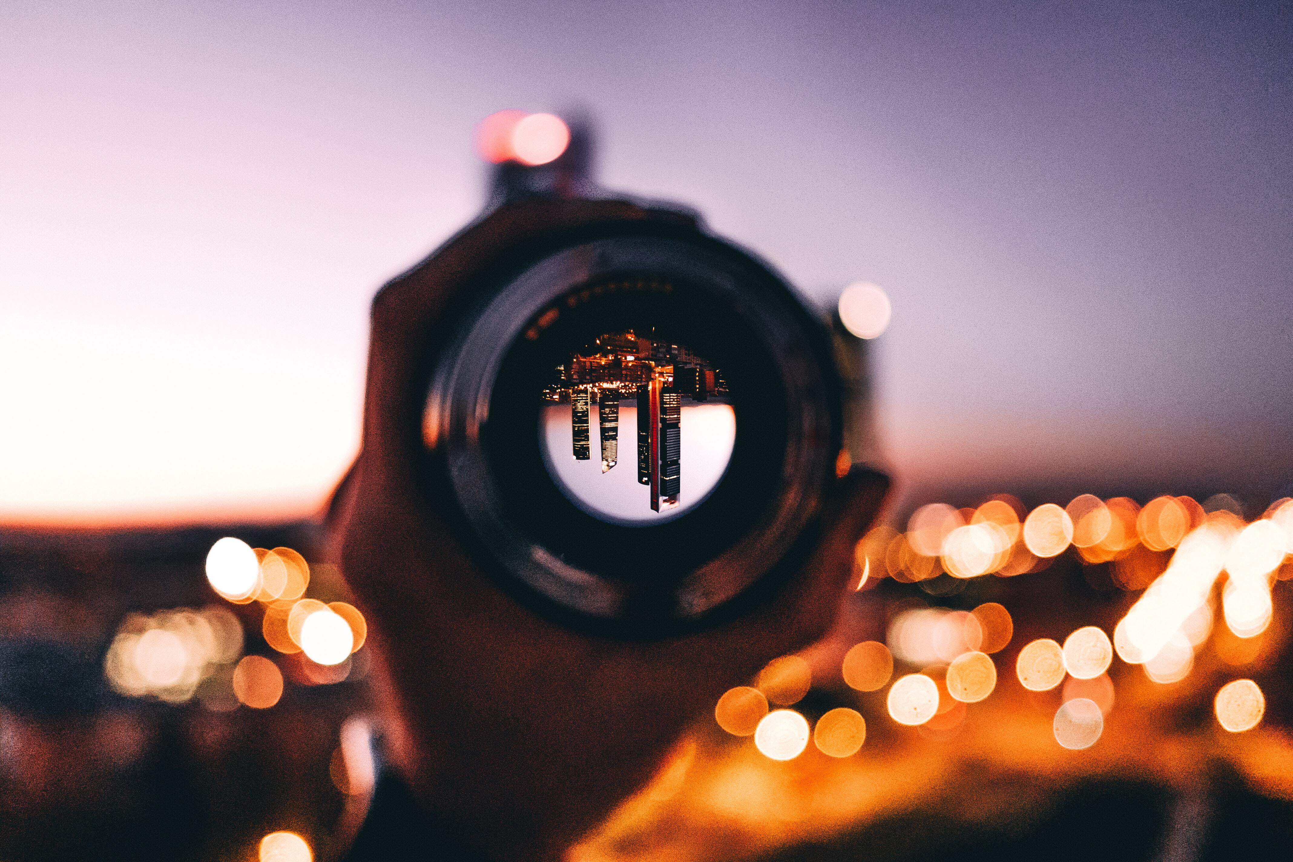 Photo of a camera lens showing an upside down city scape at night time.