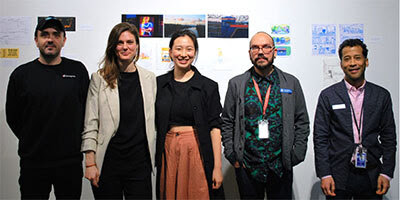 Group photo of five people standing in a line in front of art on a gallery wall