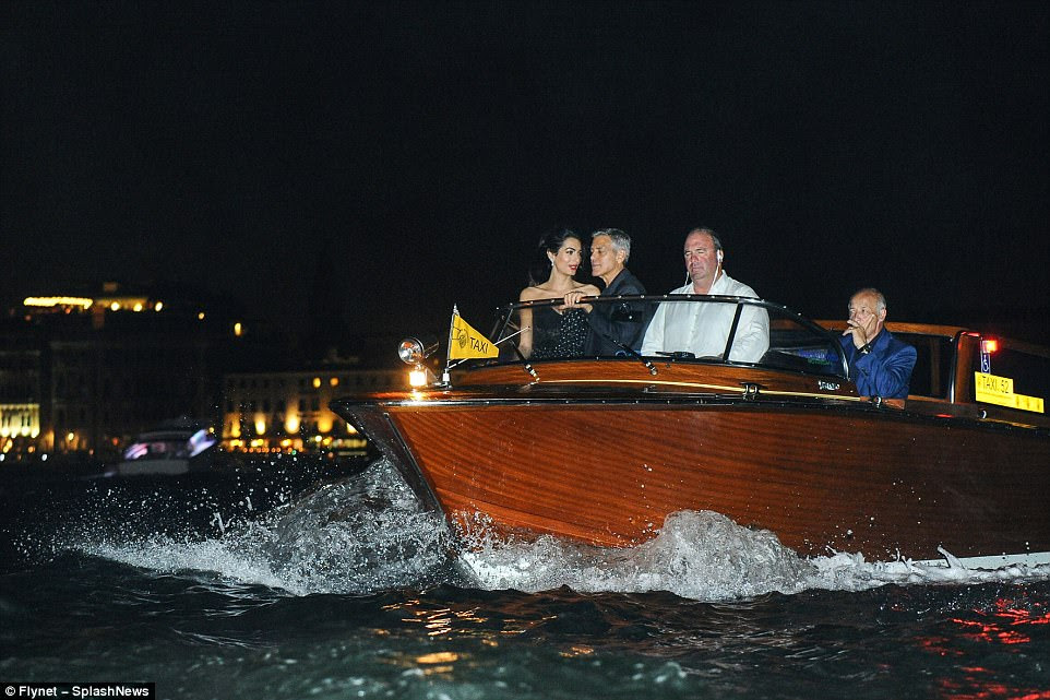 Taxi for Clooney! The couple stood at the front of their boat as it navigated the choppy Venetian waterway 