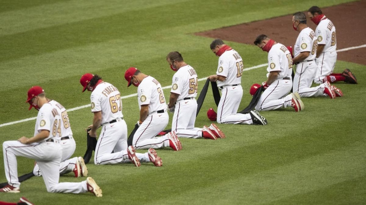 Baseball players taking a knee.