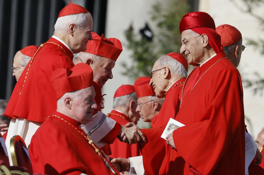Catholic cardinals in their religious attire interact at St. Peter's Square at the Vatican.