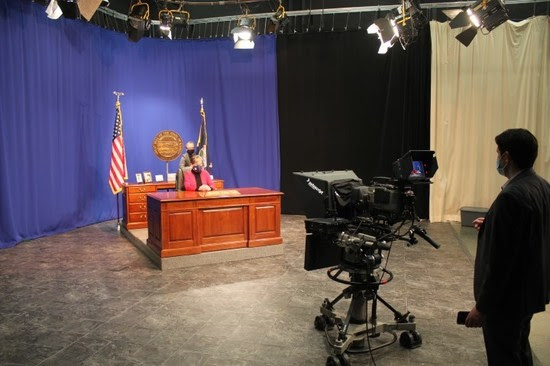 A photo from behind the television camera, showing Gov. Kelly seated at her desk before giving her State of the State speech in January 2021.