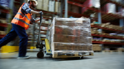 A warehouse worker moves materials with a dolly.