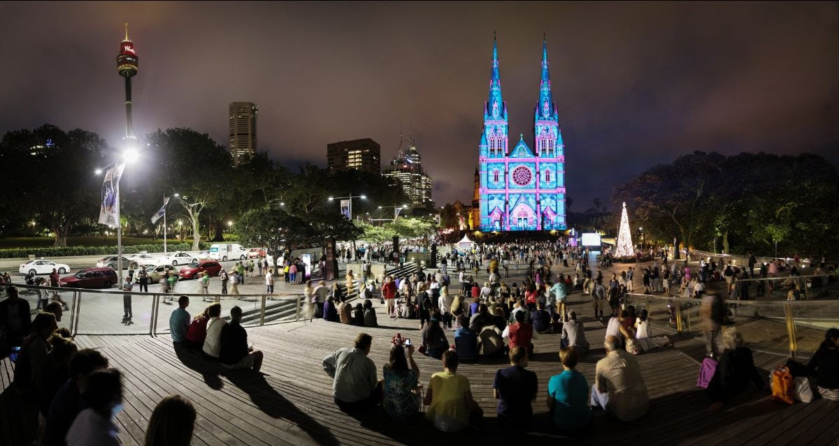 A photo of a Sydney, Australis Christmas scene with people watching the lighting of an elbaorate curch.