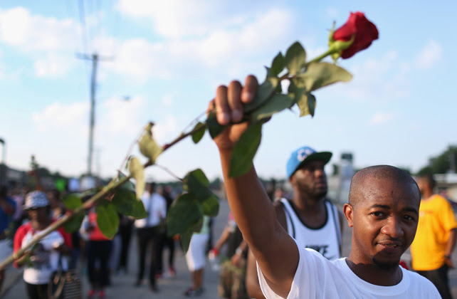 Un manifestante sostiene una rosa durante la marcha en Ferguson para pedir justicia por la muerte de Michael Brown.