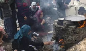 Famílias palestinas deslocadas fazem pão em forno a lenha devido à falta de gás num campo de refugiados em Rafah, na Faixa de Gaza, este sábado.  O número de vítimas na Faixa de Gaza aumentou para 20.258 mortos e 53.688 feridos desde