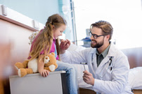 Caucasian Doctor Treating Young Caucasian Girl Holding a Teddy Bear