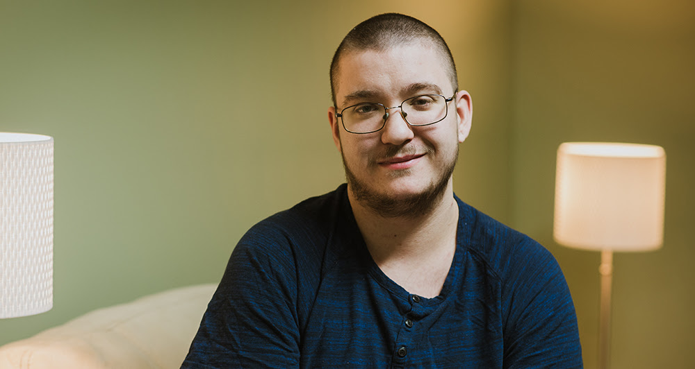 Photo of a smiling Chance. He is wearing a dark blue t-shirt and glasses.