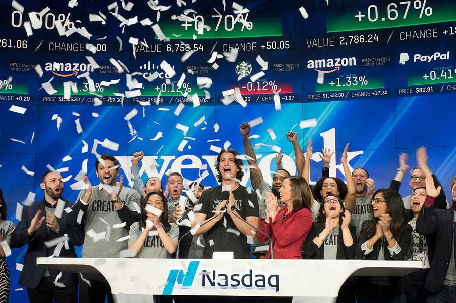 Adam Neumann, center, co-founder and CEO of WeWork, attends the opening bell ceremony at Nasdaq in New York. He is surrounded by other people cheering and there is confetti falling.