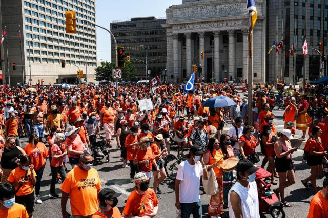 Rally participants march down Portage Ave in Winnipeg in support of residential school survivors and the families of missing and murdered Indigenous children.