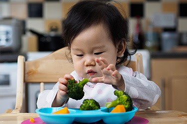baby in high chair with veggies