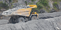 A large truck carries rocks at an above ground mine.  