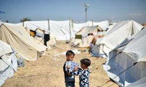 Dos niños cargan botellas de agua en un campo de refugiados de la UNWRA en Jan Yunis, al sur de Gaza.