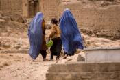 Two Afghan women wearing burqa and a girl walking