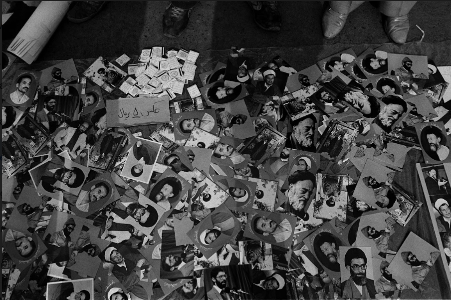 A black and white photo by Kaveh Kazemi shows a floor strewn with portraits