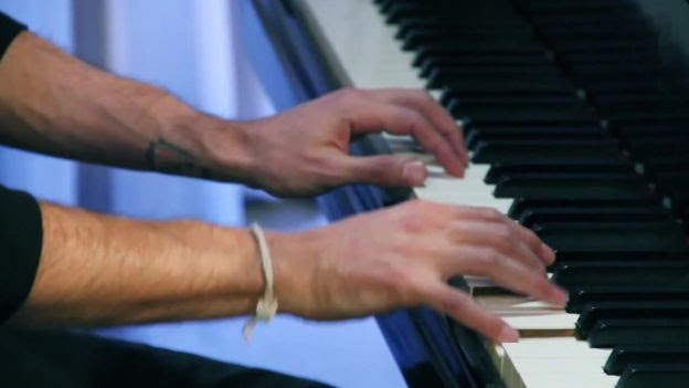 Imagem mostra as mãos do pianista e um piano