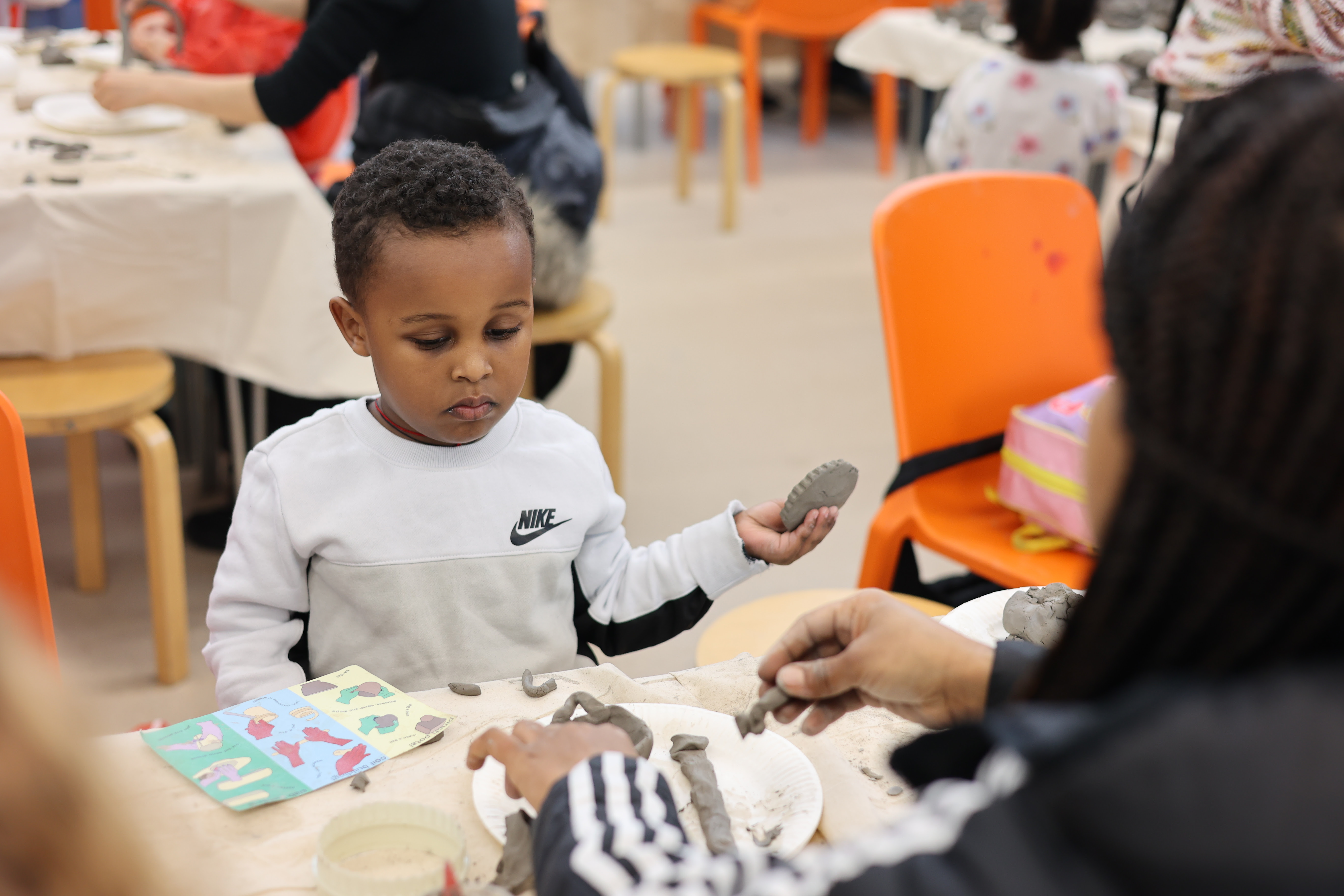 a child playing with clay while watching an adult across from them