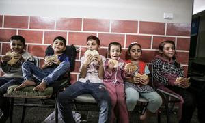 Niños de familias refugiadas en una escuela de la UNRWA en Gaza comen pan distribuido por el Programa Mundial de Alimentos (PMA).