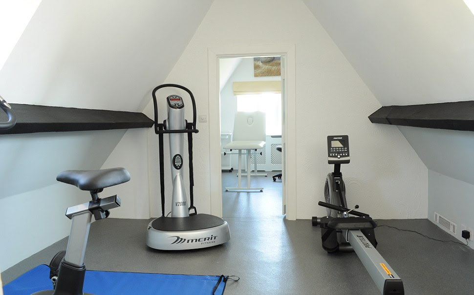 The modern-looking gym at Happisburgh Manor features a rowing machine and a bike. It also has a massage bed in the adjacent room