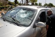 An Israeli police officer looks on at a car on where the windows were smashed by a stones thrown by Palestinian Arabs near Tekoa. (archive)