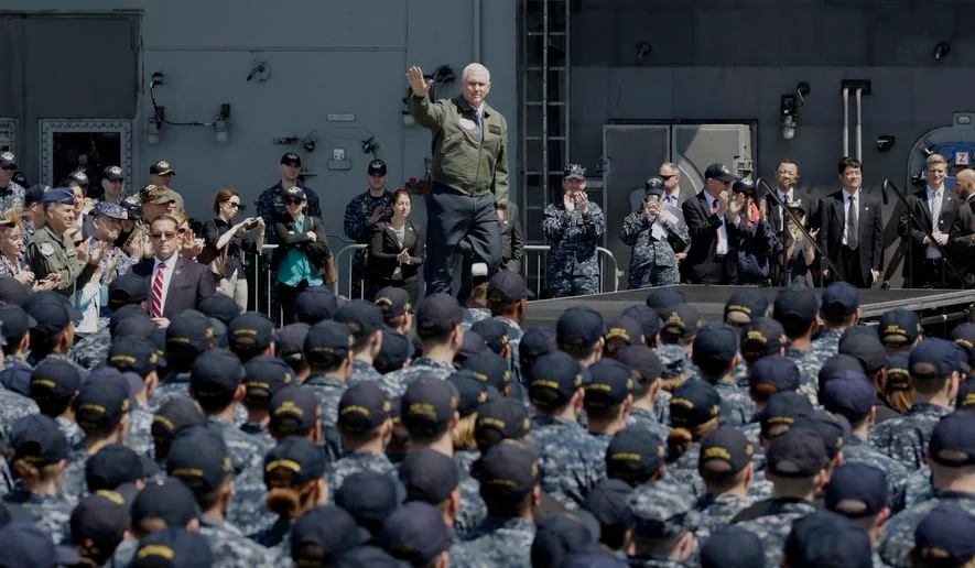 U.S. Vice President Mike Pence, center top, waves before he speaks to U.S. servicemen and Japanese Self-Defense Forces personnel on the flight deck of U.S. navy nuclear-powered aircraft carrier USS Ronald Reagan at the U.S. Navy's Yokosuka base in Yokosuka, south of Tokyo, Wednesday, April 19, 2017. (AP Photo/Eugene Hoshiko)