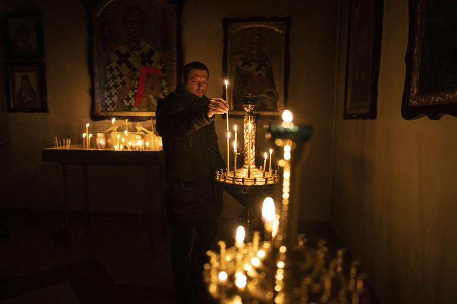 A man lights a candle during a Sunday service in an Orthodox church in Bucha, in the outskirts of Kyiv, Ukraine, Sunday, April 10, 2022.