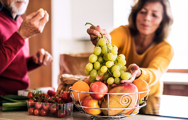 A woman and man eating grapes.