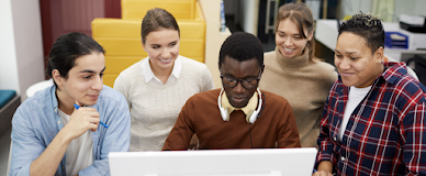 Internship participants sitting around a single computer screen.