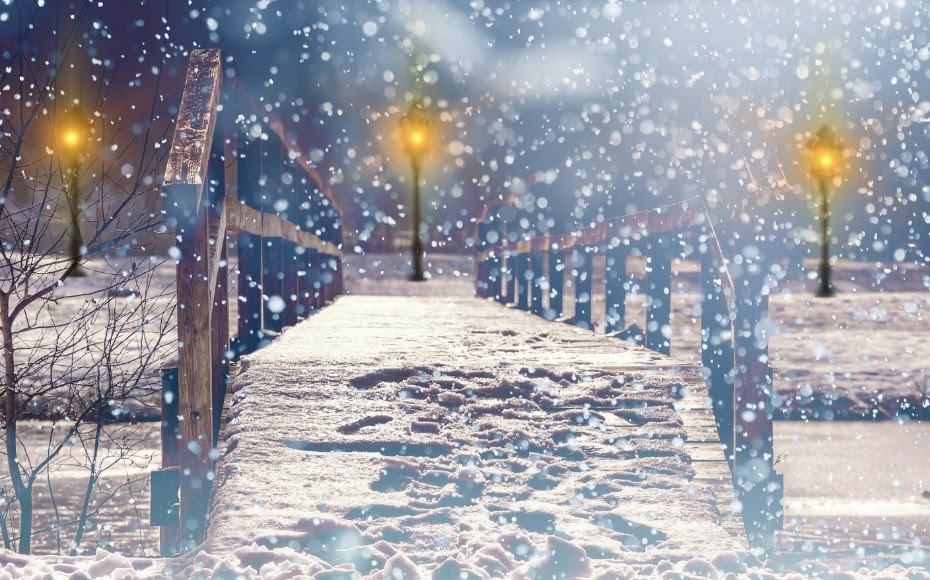 Snow falling on a bridge at night