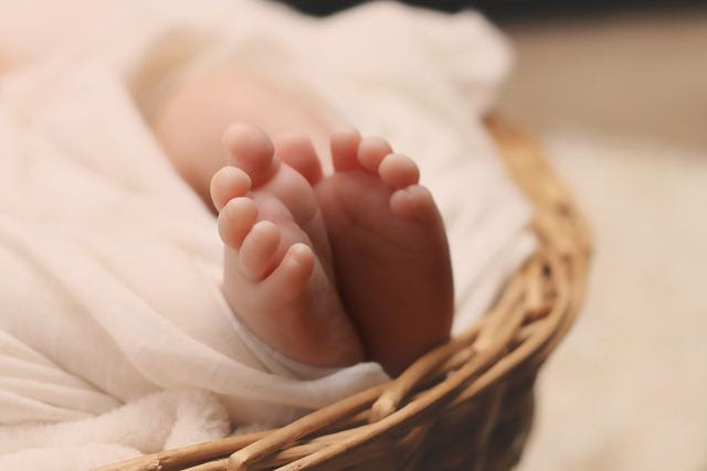 Close up picture of a light-skinned baby's feet, surrounded by blankets in a basket.