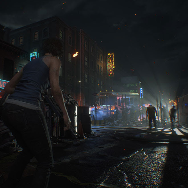 At night, Jill Valentine approaches a fenced barricade on a downtown Raccoon City street with zombies on either side of the fence.