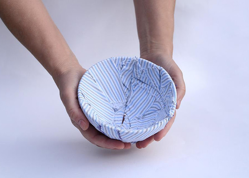 A photo of a pair of hands holding a bowl that's covered in striped fabrics.