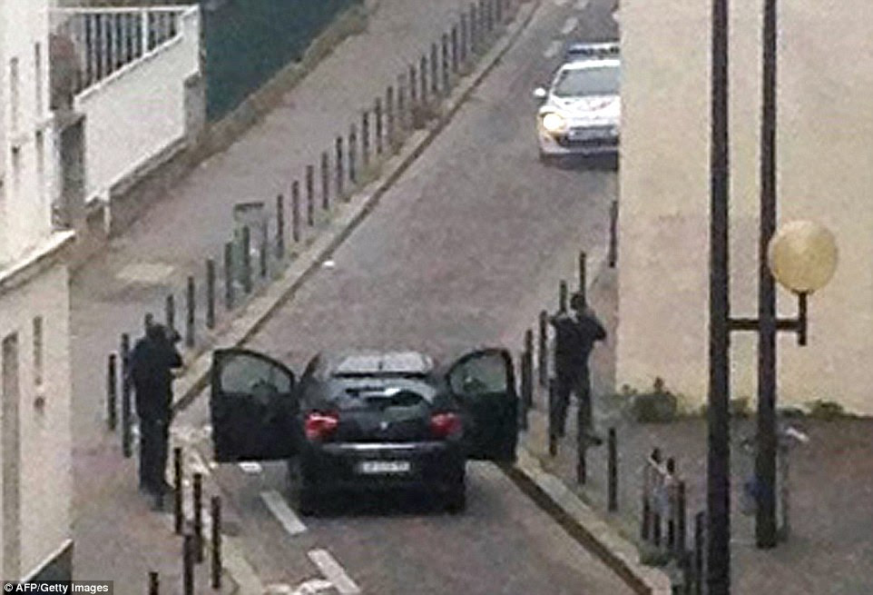 At large: The gunmen are seen near the offices of the French newspaper Charlie Hebdo before fleeing in a car. They remain on the loose
