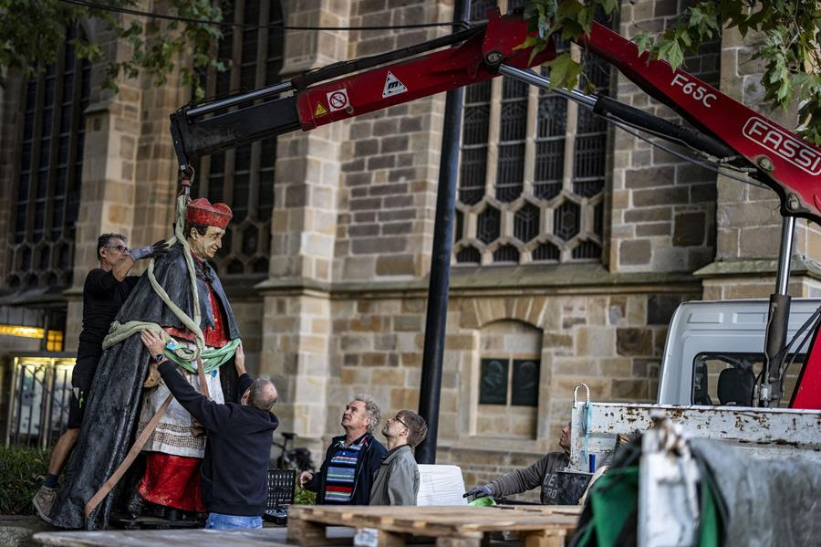 Men oversee the removal of a statue.