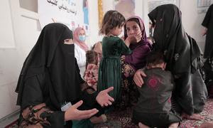 Una asesora nutricional asesora a una madre y a sus hijos en una aldea afgana.