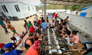 Migrantes y refugiados cargando sus teléfonos en un enchufe de la Estación de Acogida de Migrantes tras cruzar la selva del Darién.