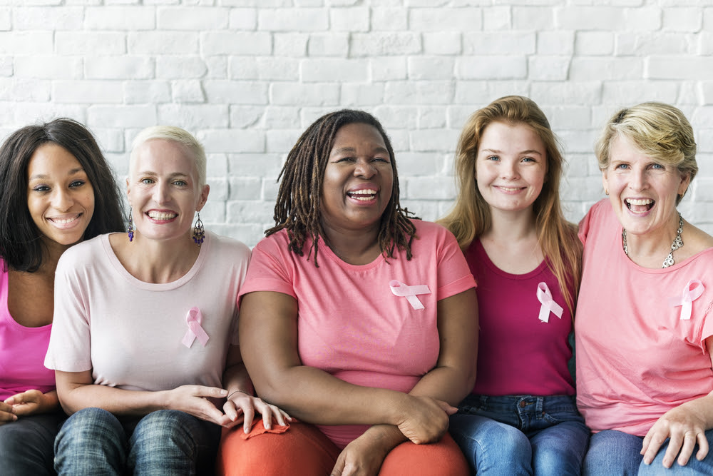diverse group of women wearing tshirts that are various shades of pink with breast cancer awareness ribbons