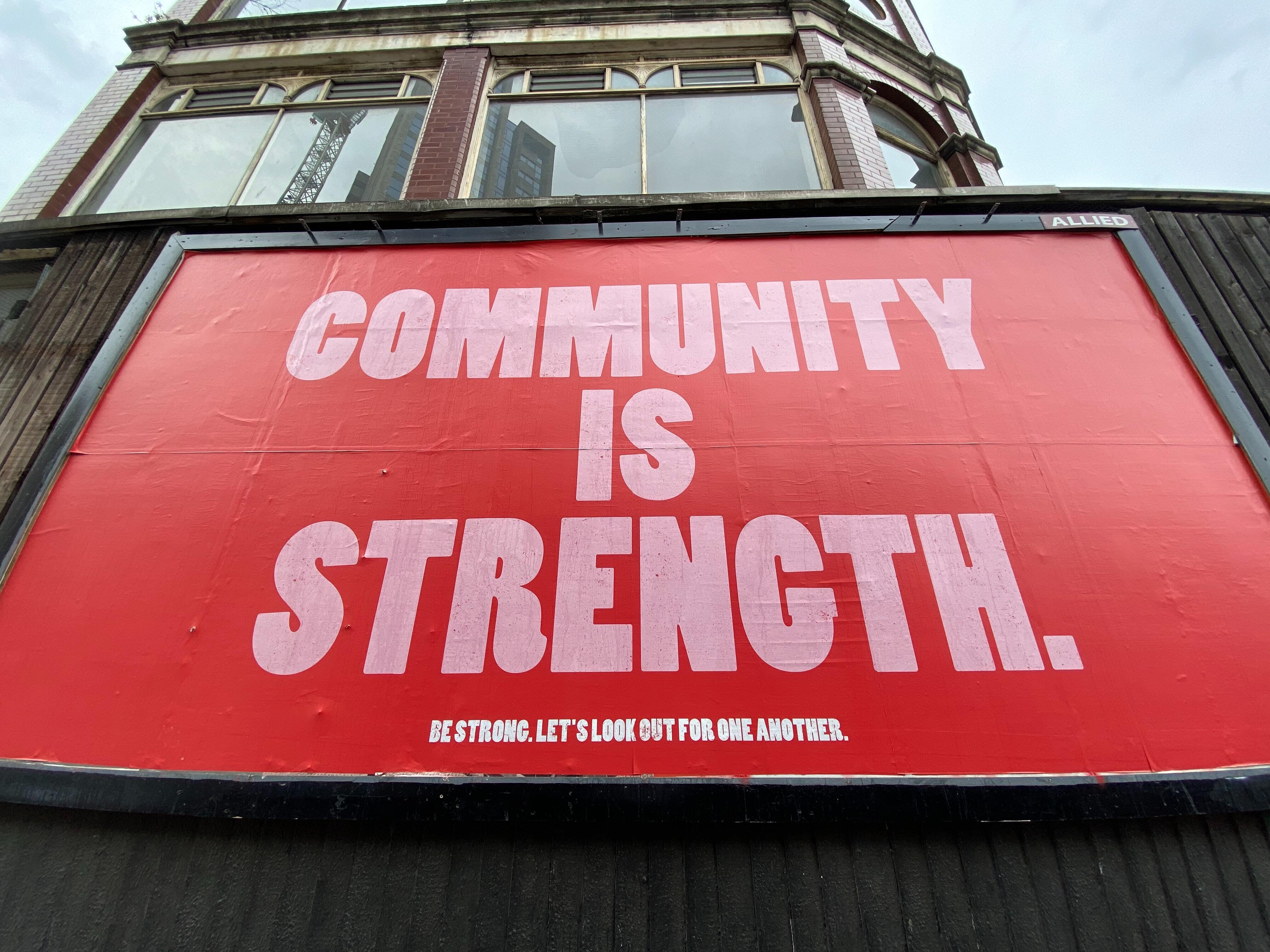 Red billboard with the words "community is strength" written on it.
